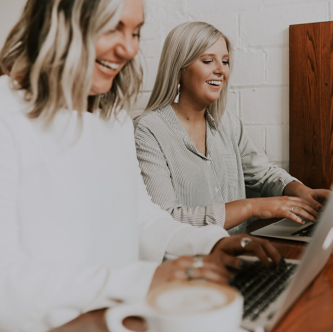 two women using laptops