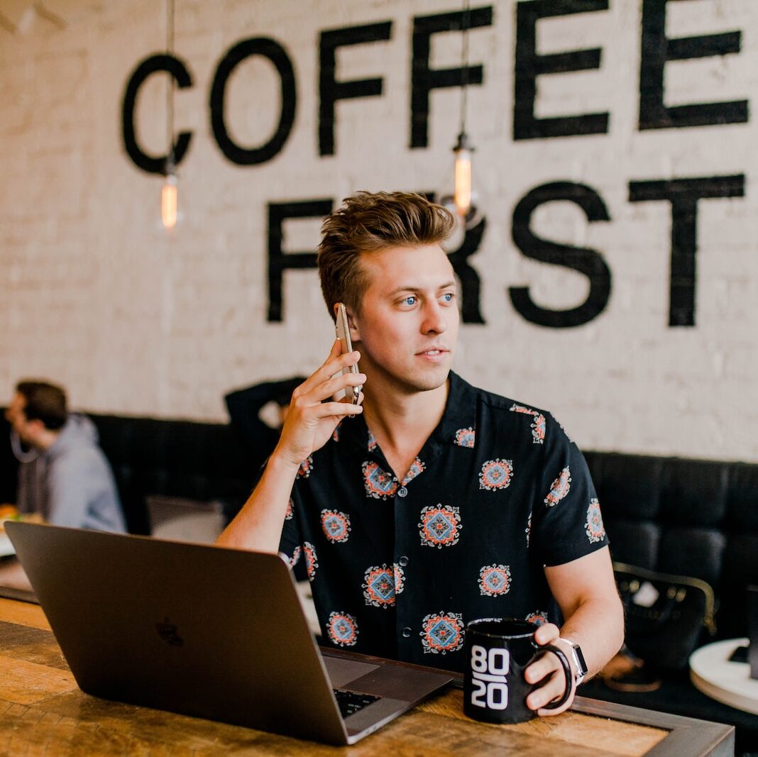 man holding phone white using MacBook